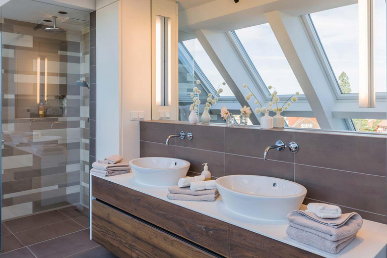 Bagno moderno con due lavandini e un ampio specchio su cui si riflettono le finestre