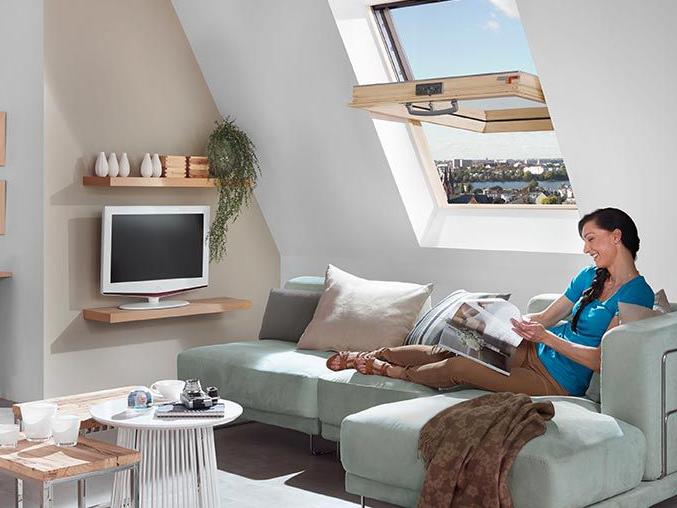 Eine Frau liegt auf der Couch, liest eine Broschüre und lüftet das Wohnzimmer mit ihrem RotoQ Schwingfenster aus Holz